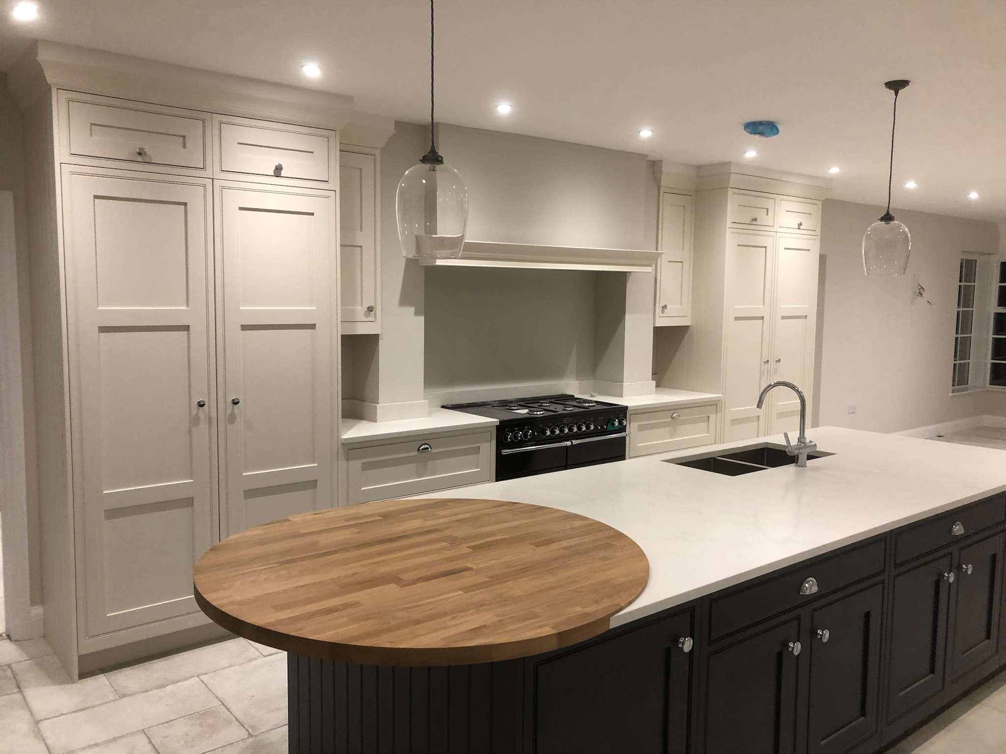 Light shaker kitchen with a contrasting dark island and circular timber breakfast surface