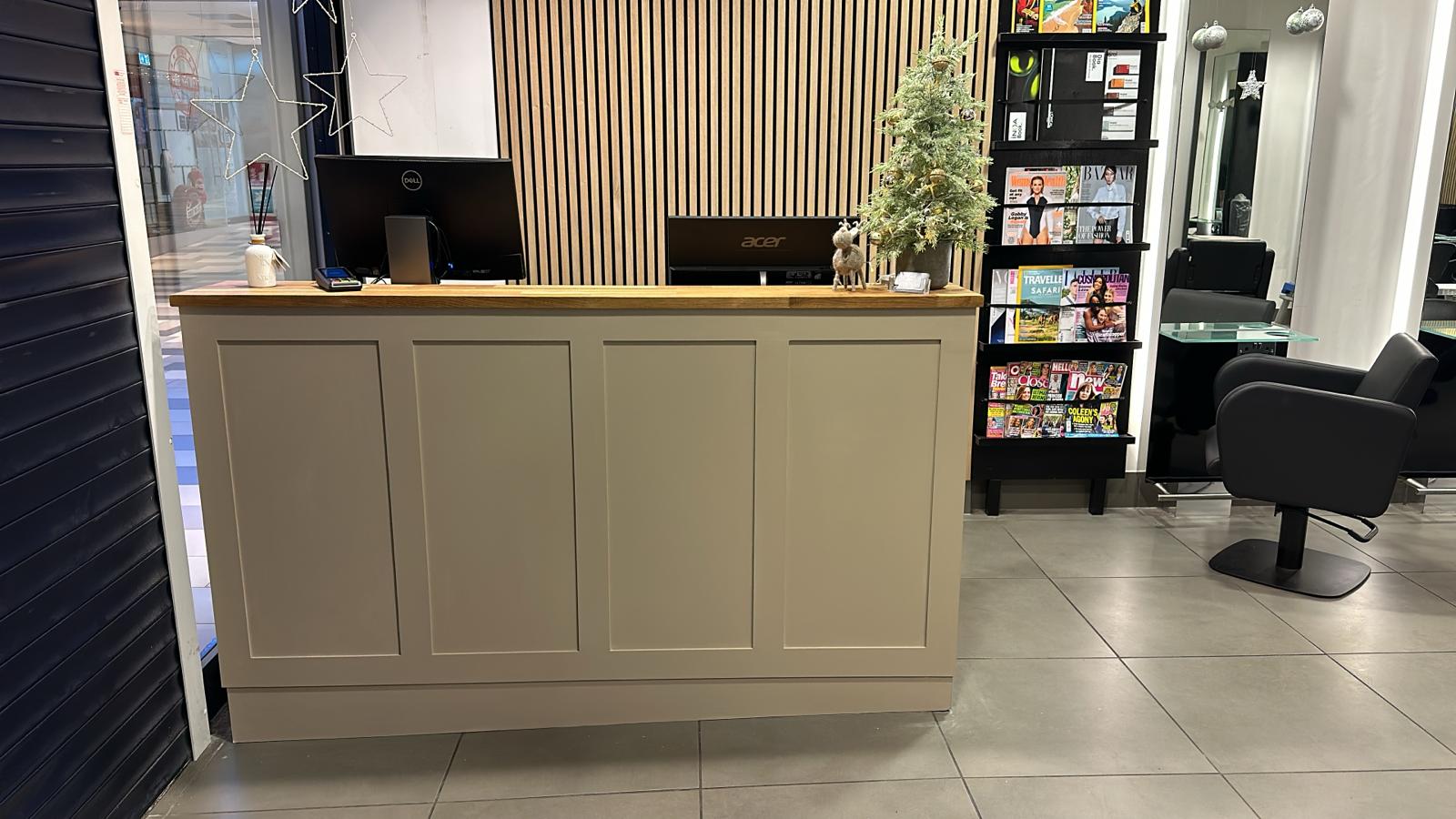 Painted panelled reception counter with timber top and slatted wall backdrop